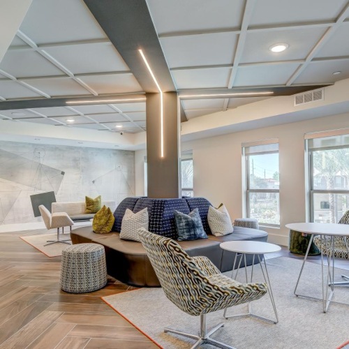 a lounge area with a rug, chairs and windows