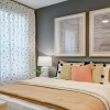 a bedroom with a nightstand, dresser and a window