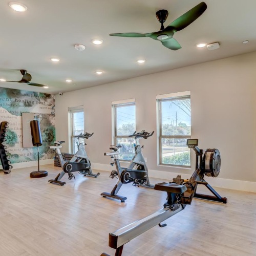 a gym with large windows, a tv, and exercise equipment