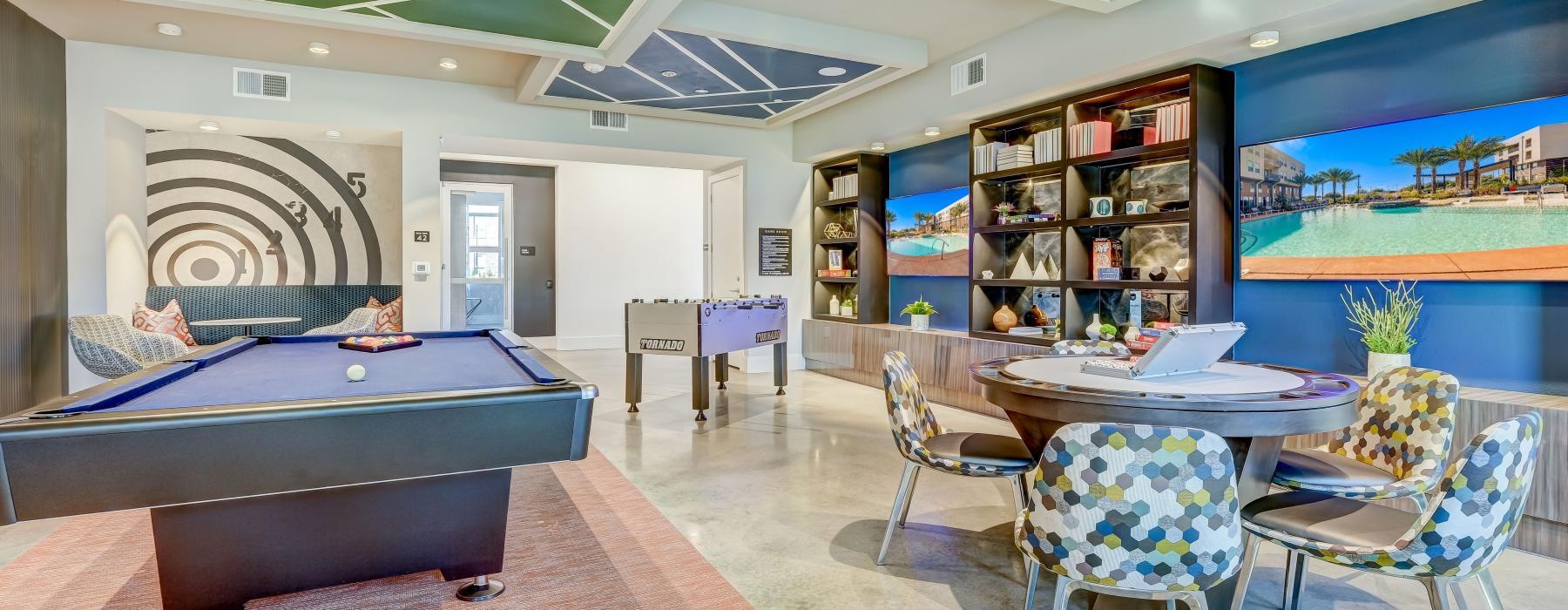a room with a pool table, chairs, tv's and a fooseball table